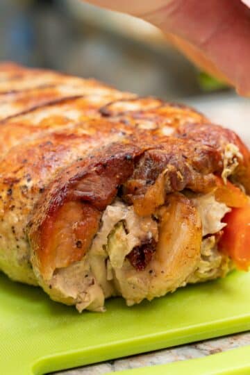 Smoked chicken breasts stuffed with apple and bacon on a wooden cutting board