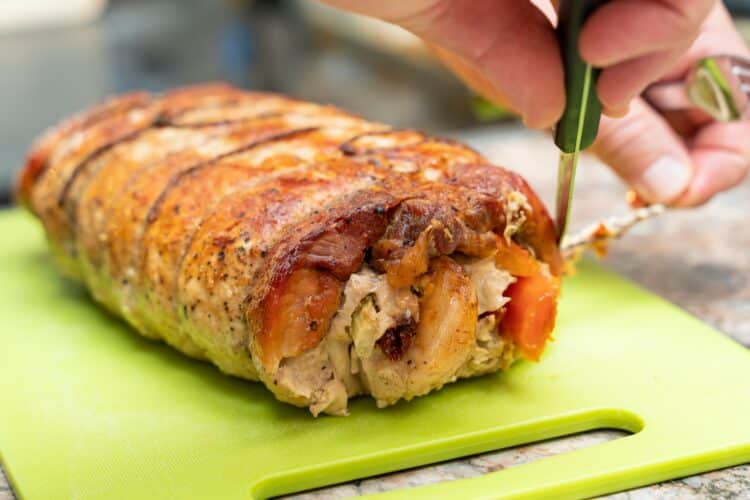 Smoked chicken breasts stuffed with apple and bacon on a wooden cutting board