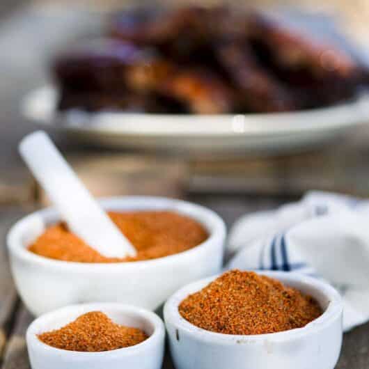 Homemade barbecue rub blend in a clear jar on a rustic table.