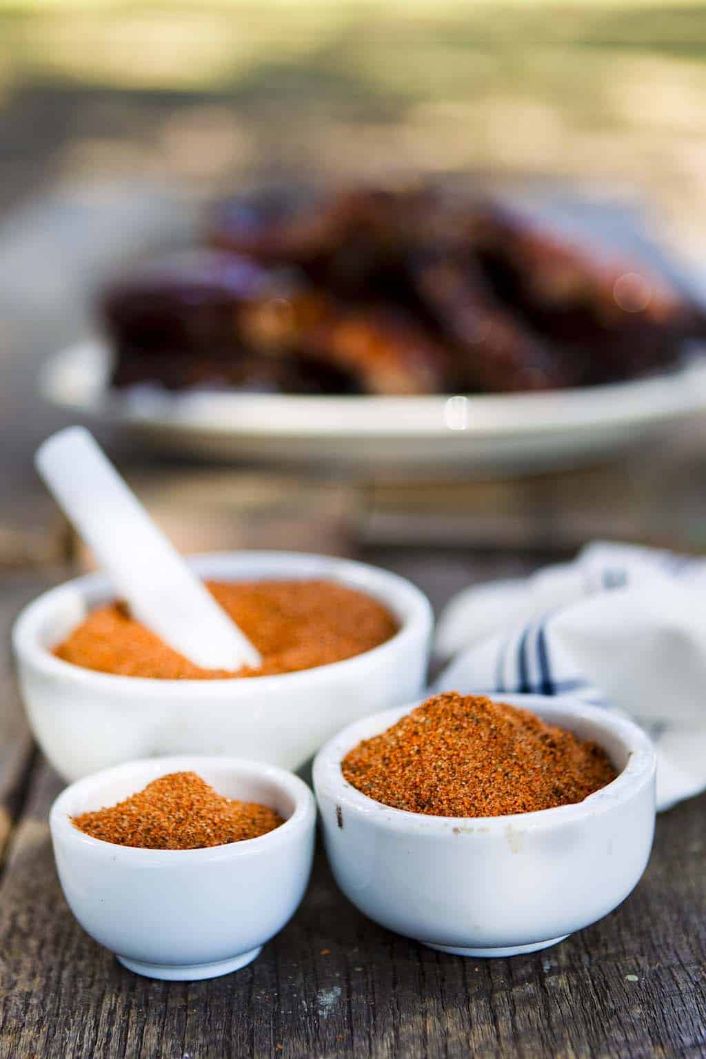 Homemade barbecue rub blend in a clear jar on a rustic table.