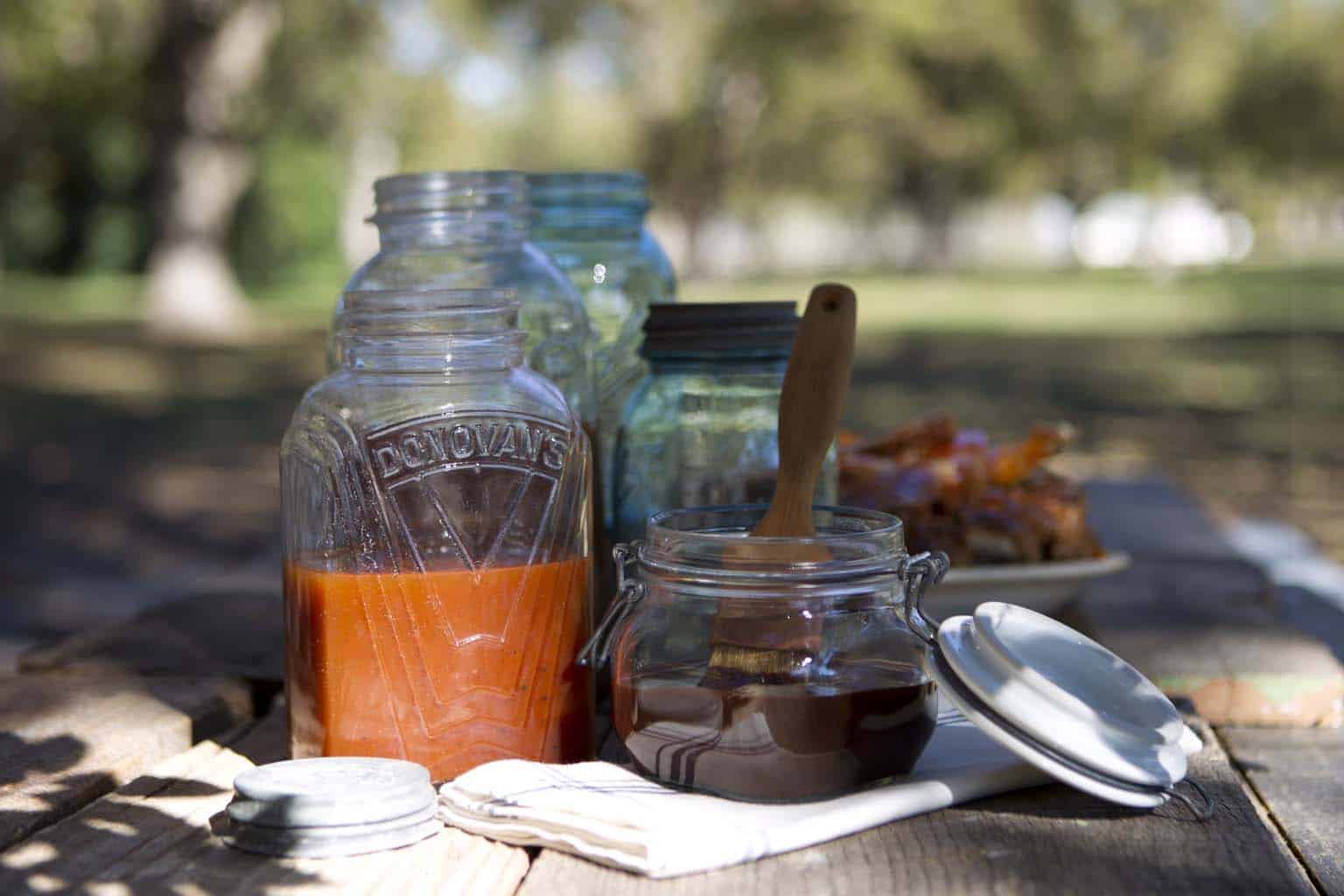 Bottle of homemade vinegar barbecue sauce with visible spices.
