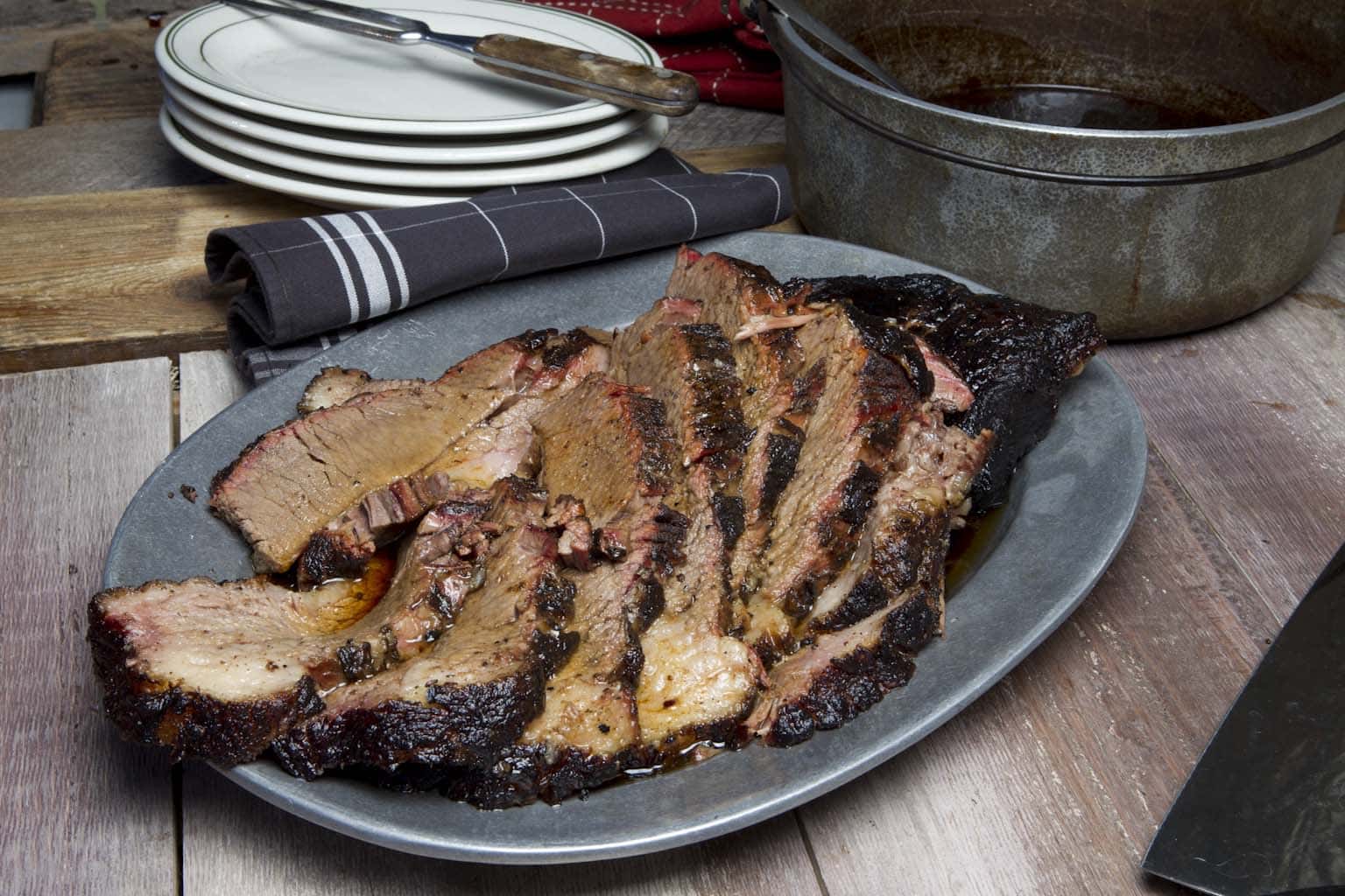 Sliced smoked brisket with burnt ends on a wooden cutting board