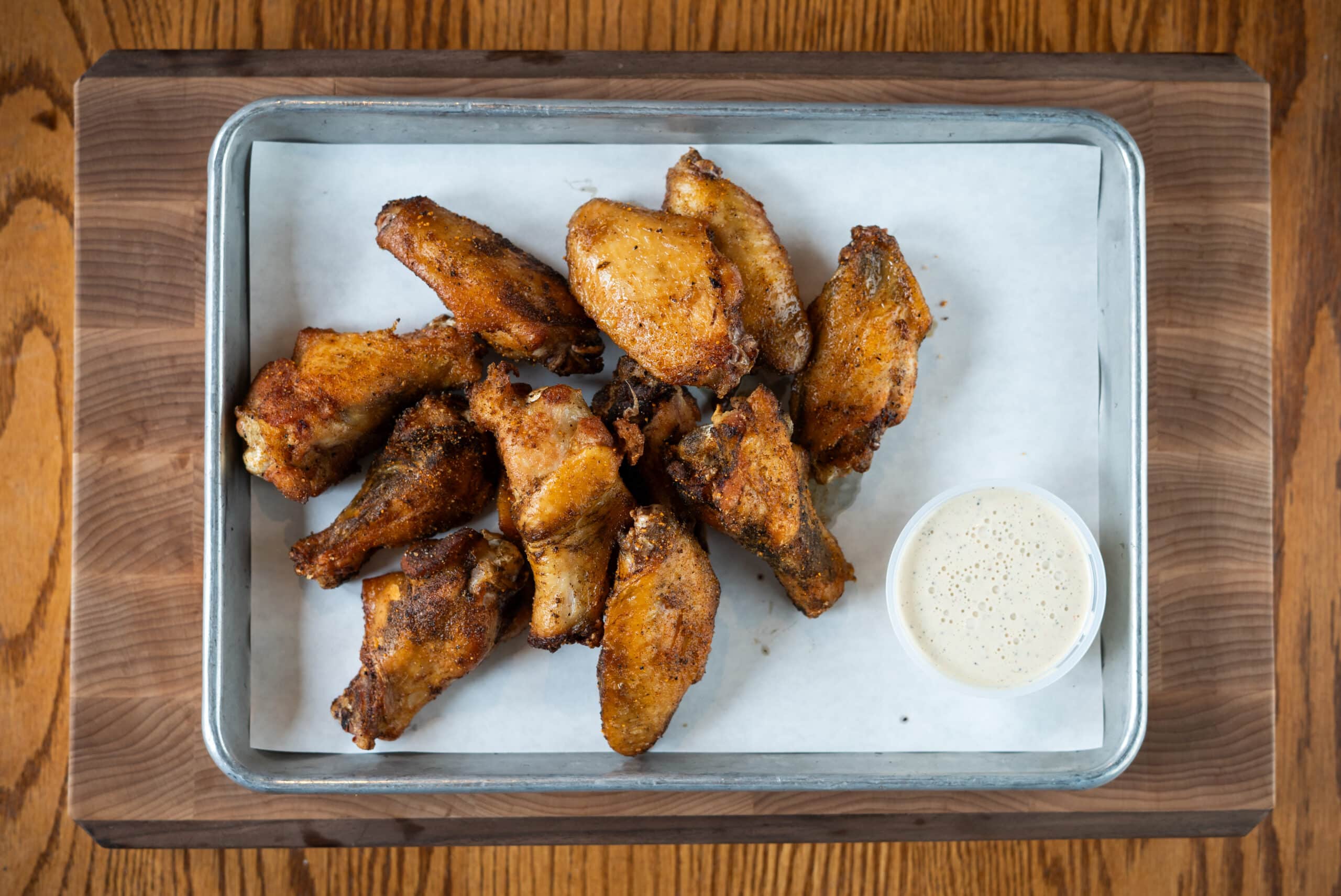 Smoked chicken wings glazed with sauce in a foil pan