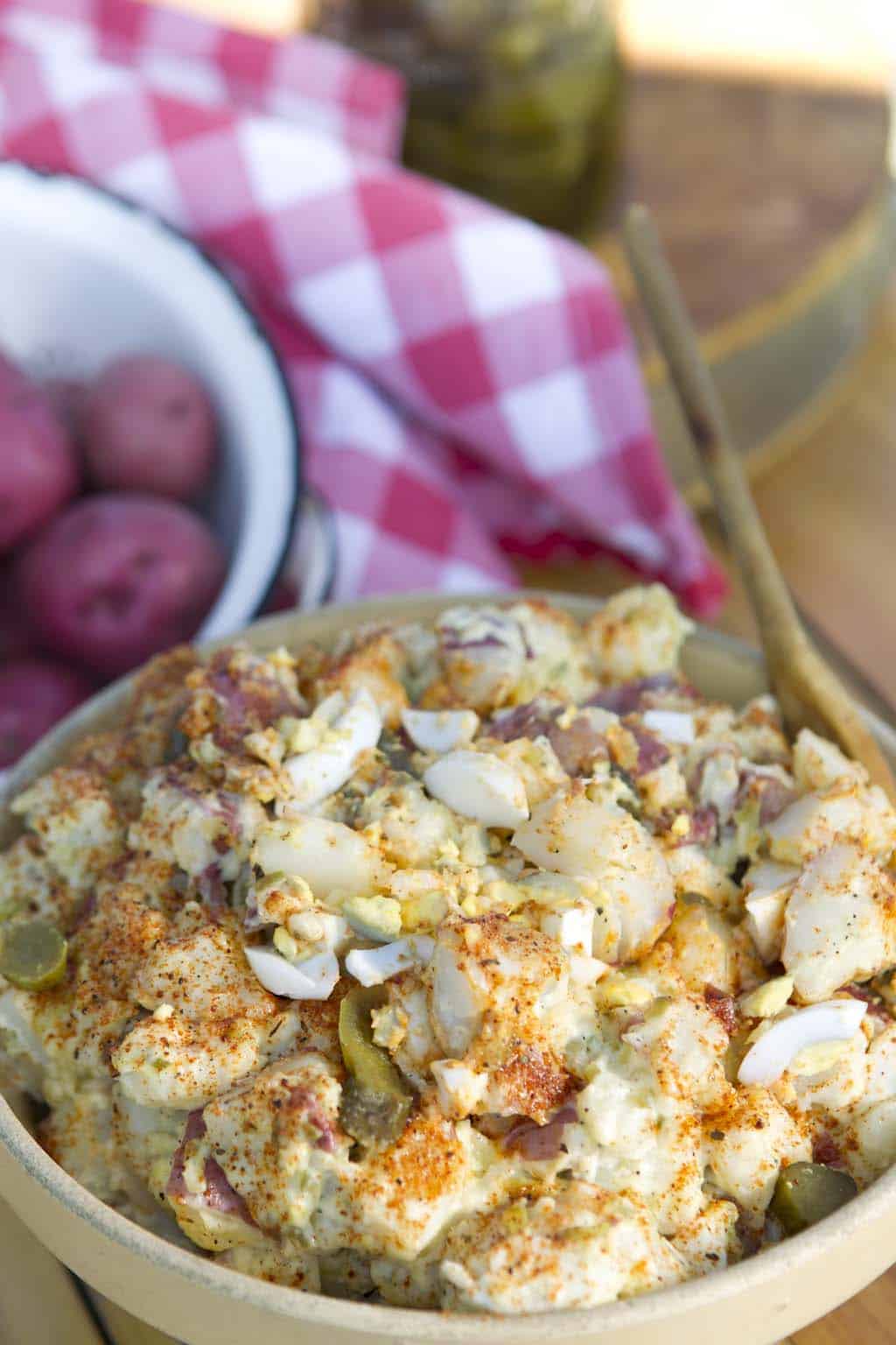 Loaded potato salad with red potatoes, cheese, bacon, and chives mixed in a creamy dressing.