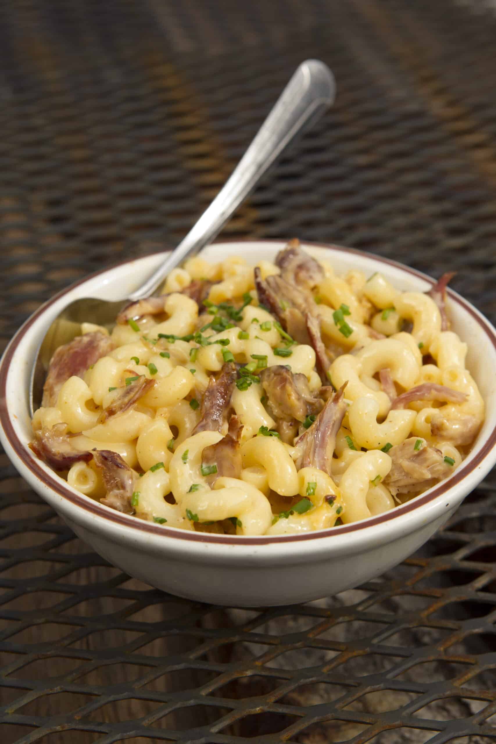 Baby back mac and cheese topped with melted cheese and rib meat in a cast iron pan.