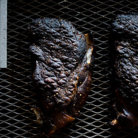 Smoked pork shoulder on a cutting board with bark and smoke ring
