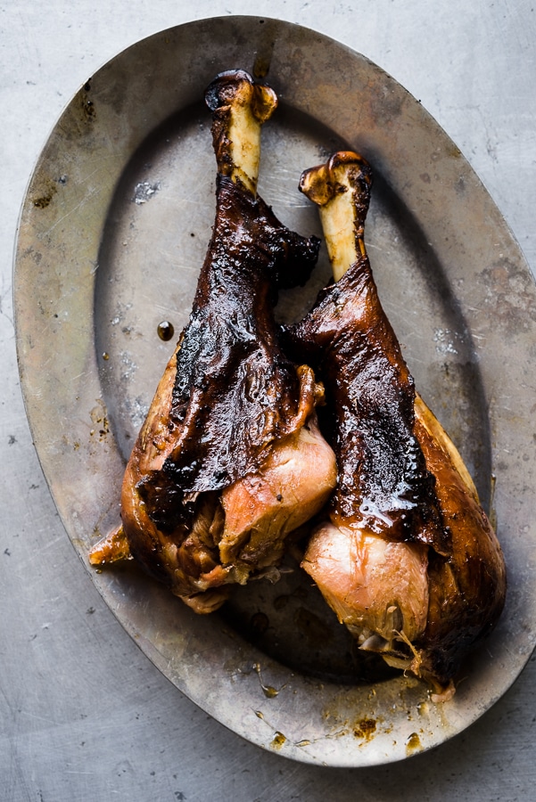 Smoked turkey drumsticks with crispy skin on a wooden platter