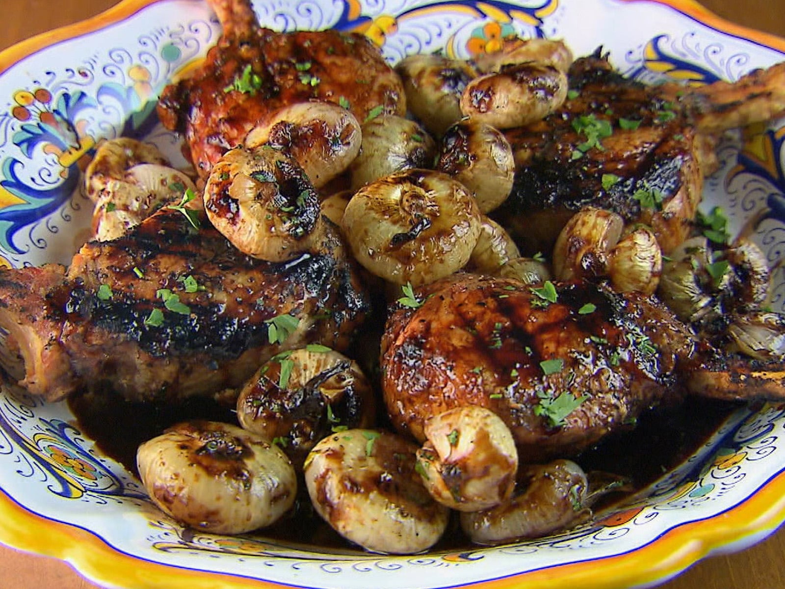 Grilled pork chops with crosshatch marks topped with glazed sweet and sour onions.