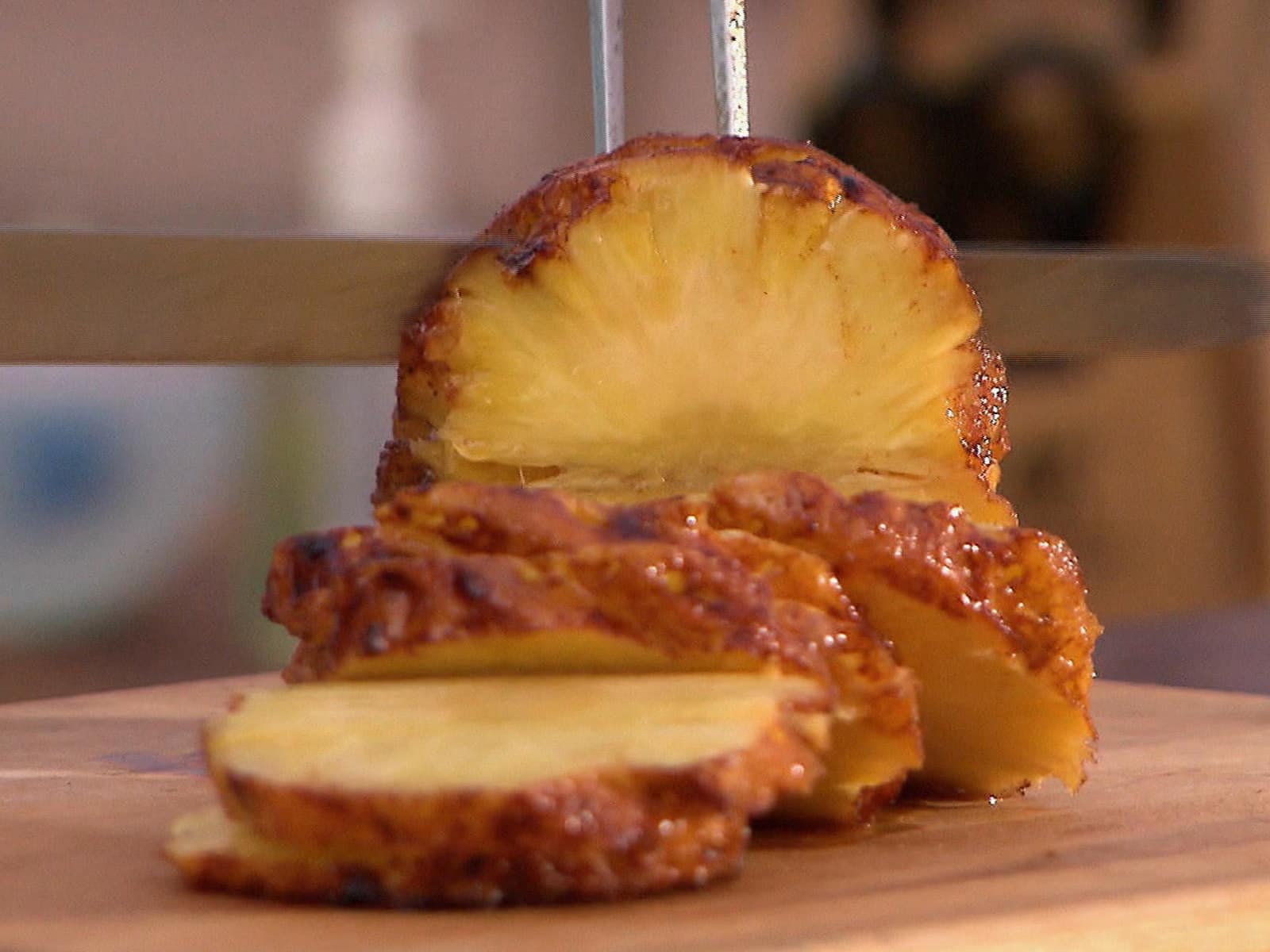 Grilled pineapple rings with salt flakes on a rustic wooden plate.