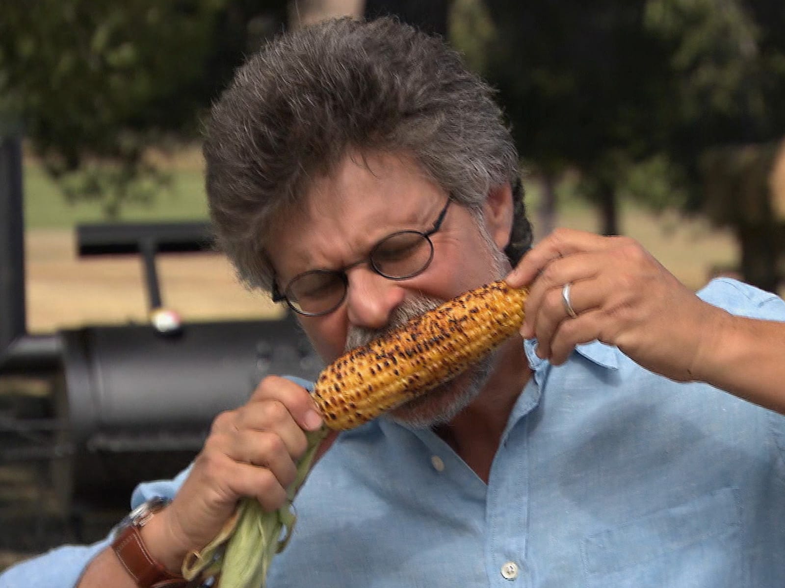 Grilled corn with coconut glaze on a rustic wooden platter.