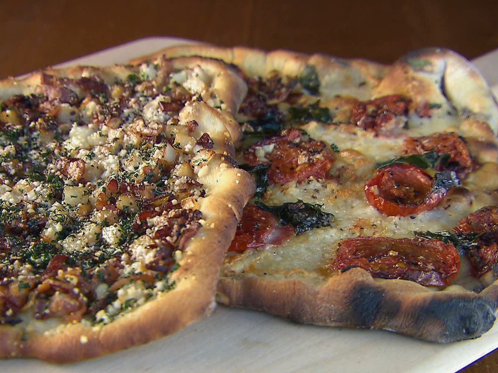 Rustic grilled pizzas topped with tomato, basil, and bubbling cheese