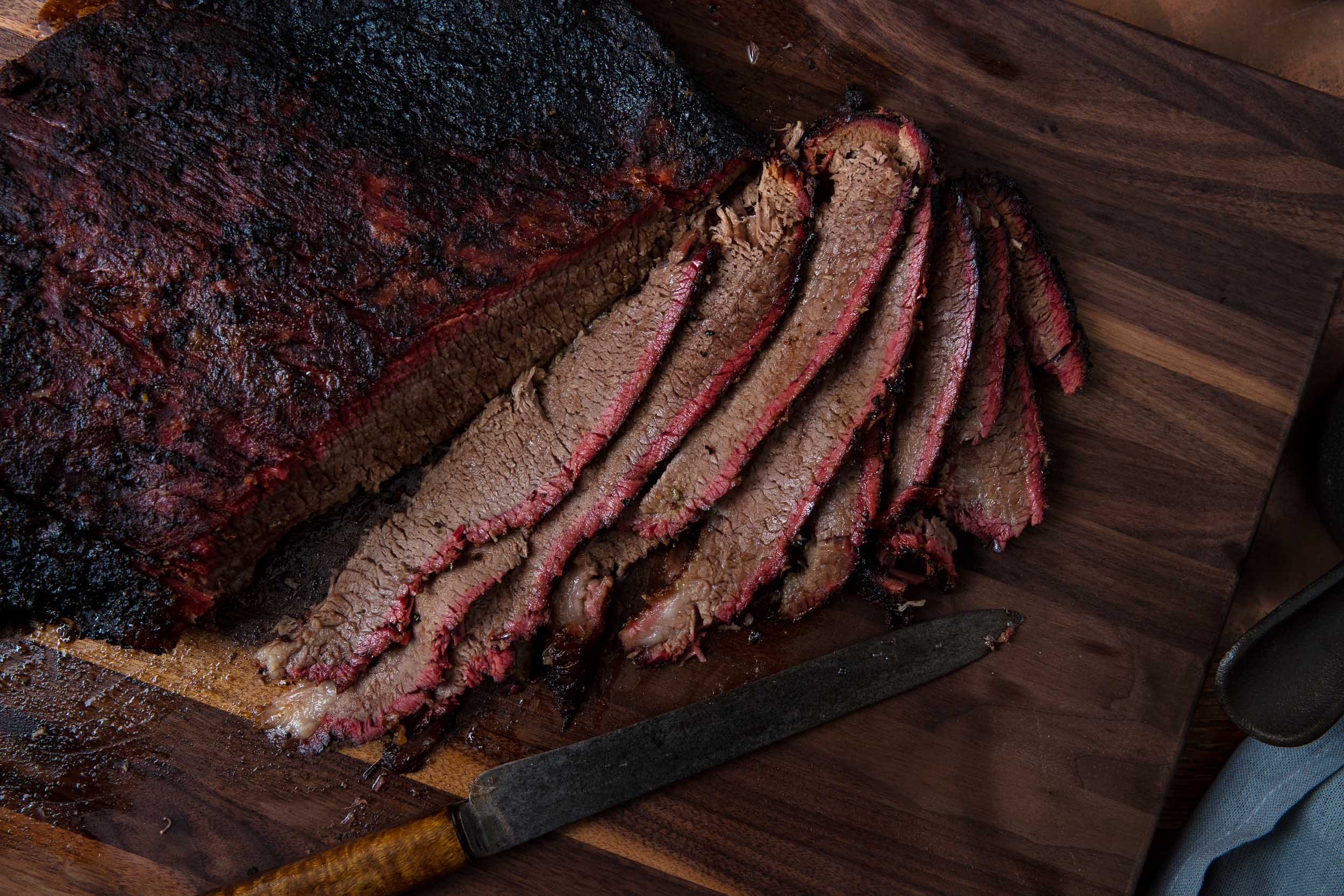 Myron Mixon’s smoked brisket sliced on a cutting board with visible smoke ring and bark