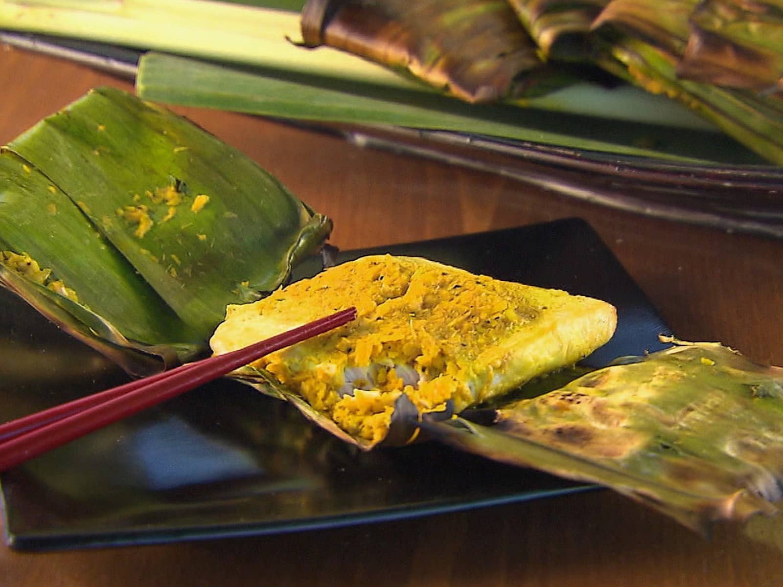Grilled banana leaf-wrapped swordfish cooking over a hot grill.
