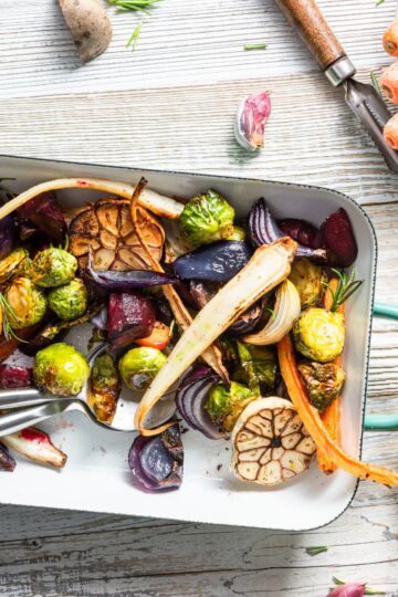Charred Brussels sprouts, carrots, beets, and roasted garlic in a cast iron skillet