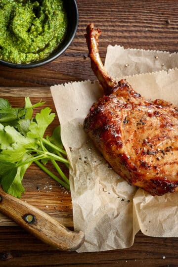 Apple and sausage stuffed pork chops plated with green beans, peppers, and onions.