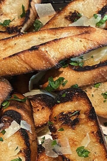 Slices of fire-grilled garlic bread with golden char and melted garlic butter.