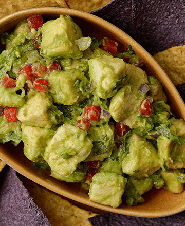 Chunky guacamole in a molcajete with visible avocado, cilantro, and diced onion.