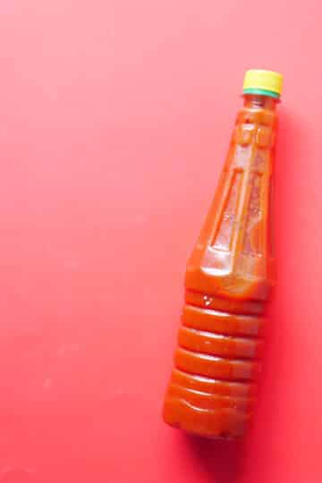 Hellfire hot sauce with visible chili slices and onions steeping in vinegar.