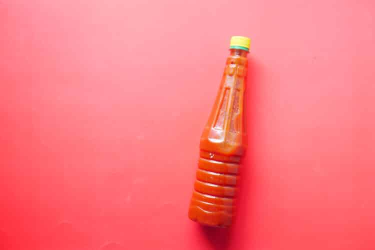 Hellfire hot sauce with visible chili slices and onions steeping in vinegar.