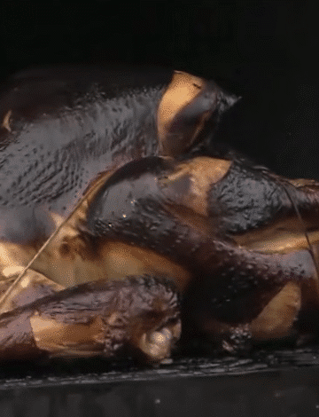 Smoked turkey breast sliced on a cutting board with rye bread and orange-mayo sauce on the side