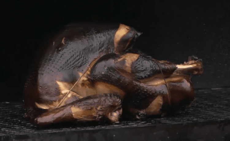 Smoked turkey breast sliced on a cutting board with rye bread and orange-mayo sauce on the side