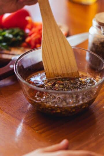 Dark beef marinade in a measuring cup with injector tool beside it.