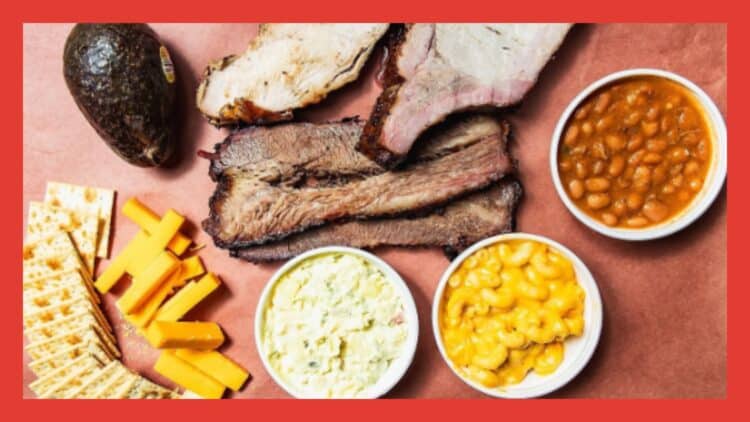 Traditional Texas barbecue sides on a wooden tray with pickles, crackers, onions, cheese, and white bread