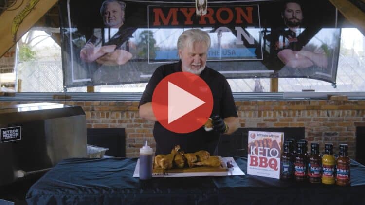 BBQ Pitmaster Myron Mixon preparing turkey legs with a smoker in the background