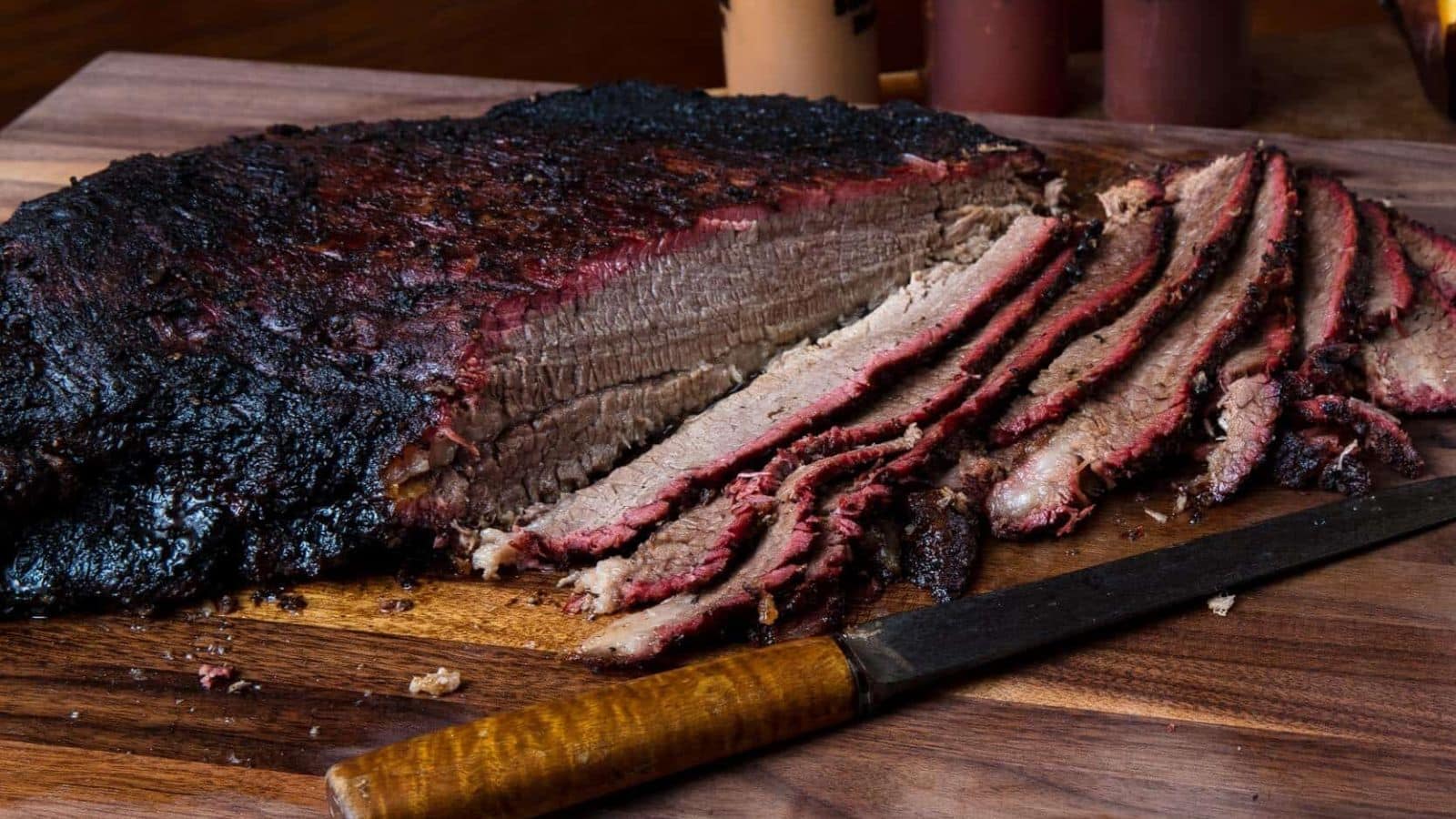 Close-up of smoked brisket slices on a wooden cutting board, juicy and glistening